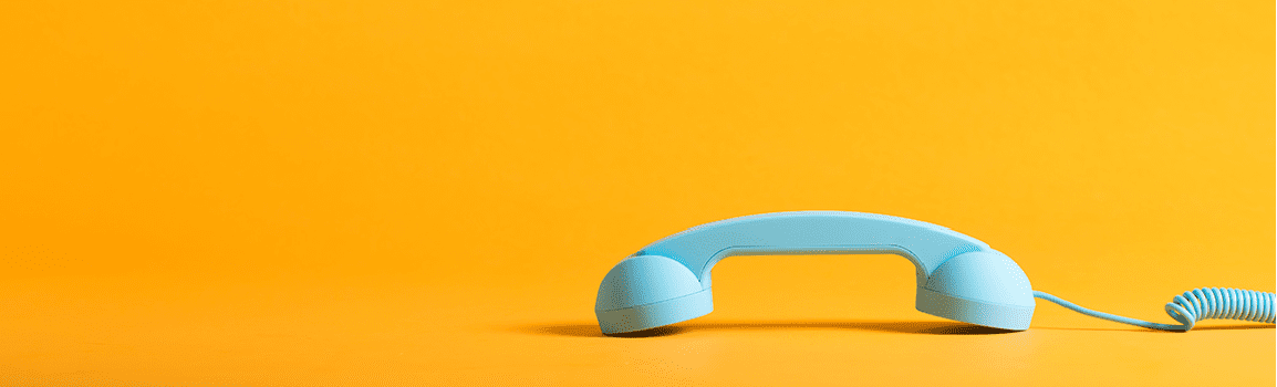 Blue corded telephone with yellow background.