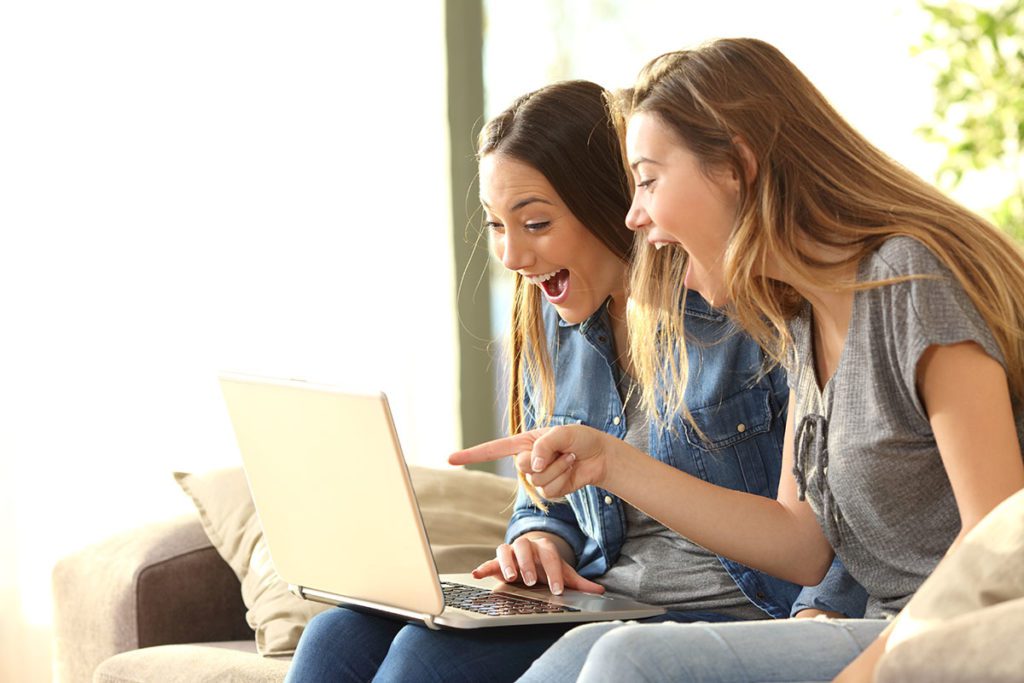 Two girls excited and pointing at computer.