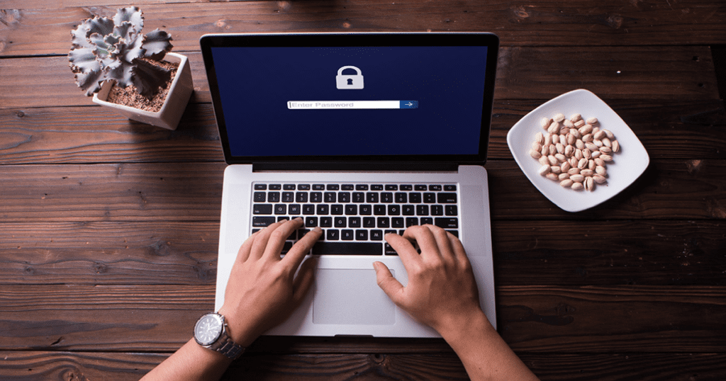 A person typing on a laptop with a locked, password-protected screen.