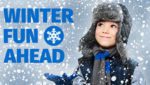 Young boy with winter hat on smiles up at falling snow.