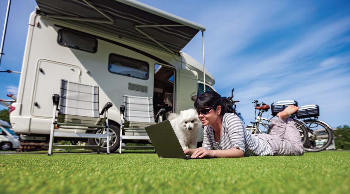 Woman using laptop by camper