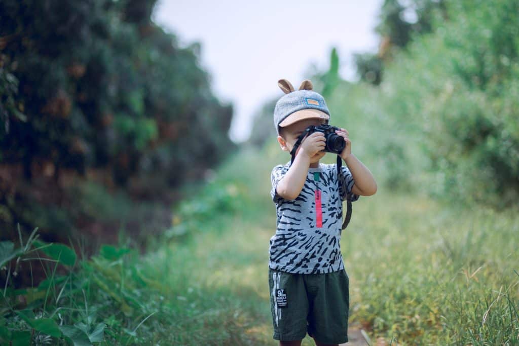 Young kid outside taking photos.