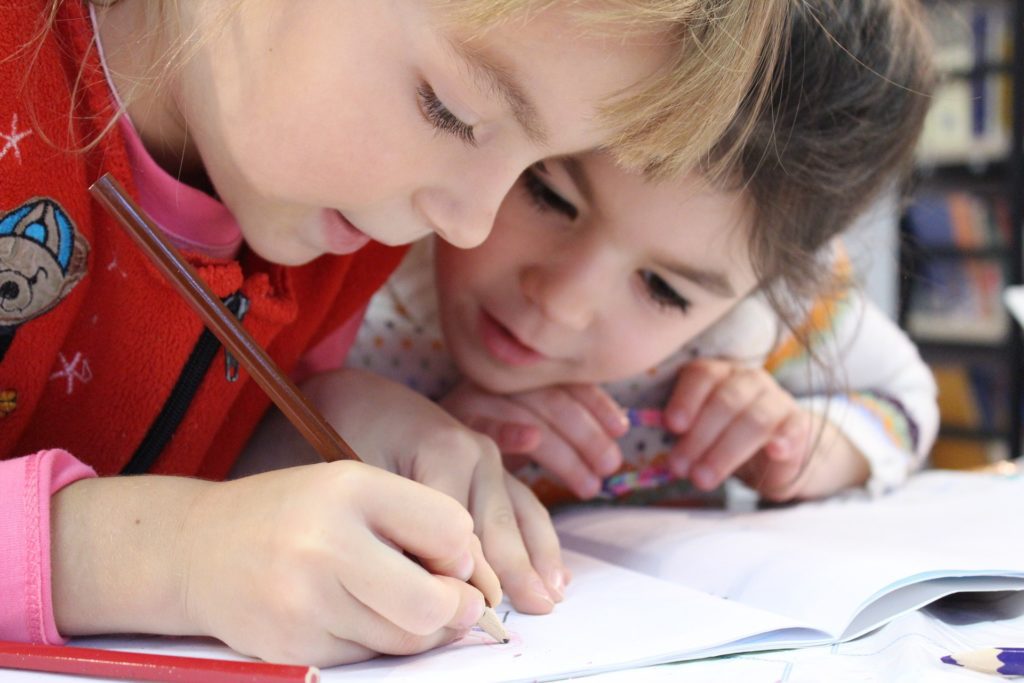 Two young girls drawing on paper.