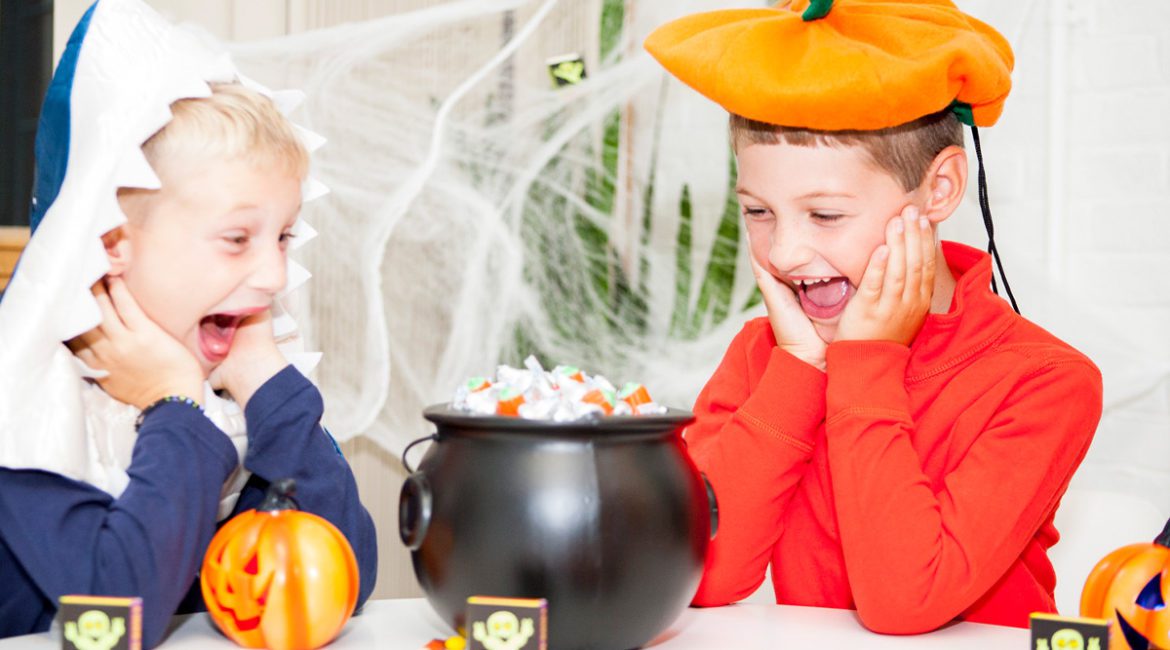 Two kids dressed for Halloween with a bowl of candy.
