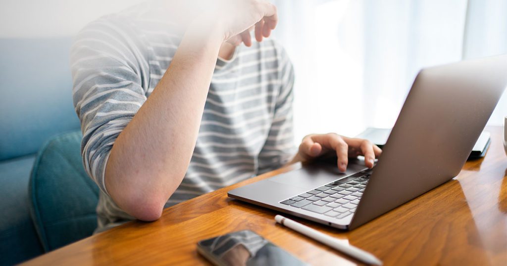 Man using laptop computer while sitting at table.