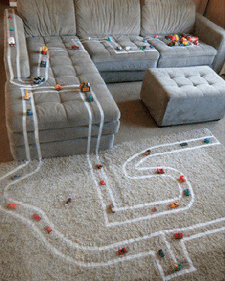 Racetrack on rug and couch with cars scattered throughout the track.