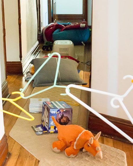 Messy hallway obstacle course in house with toys and laundry items scattered.