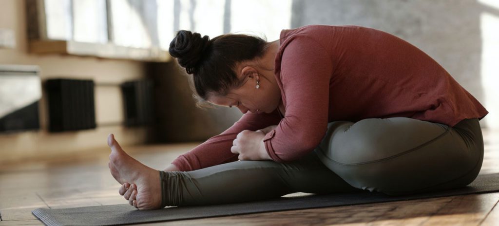 Woman exercising in yoga pose on floor.