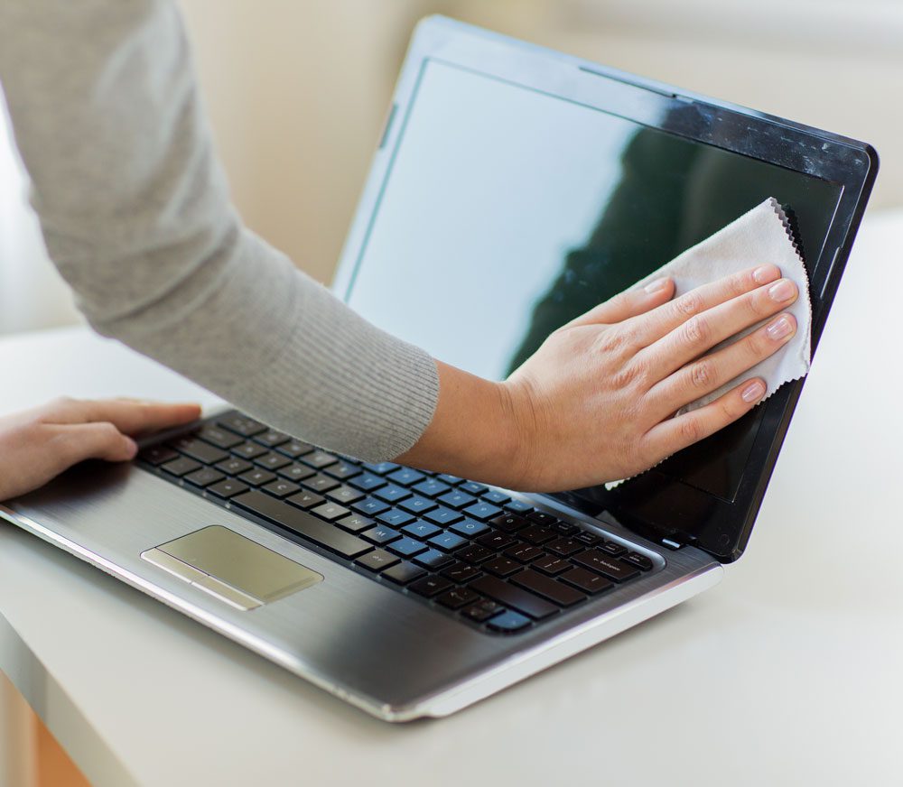 Person cleans laptop screen with microfiber cloth.