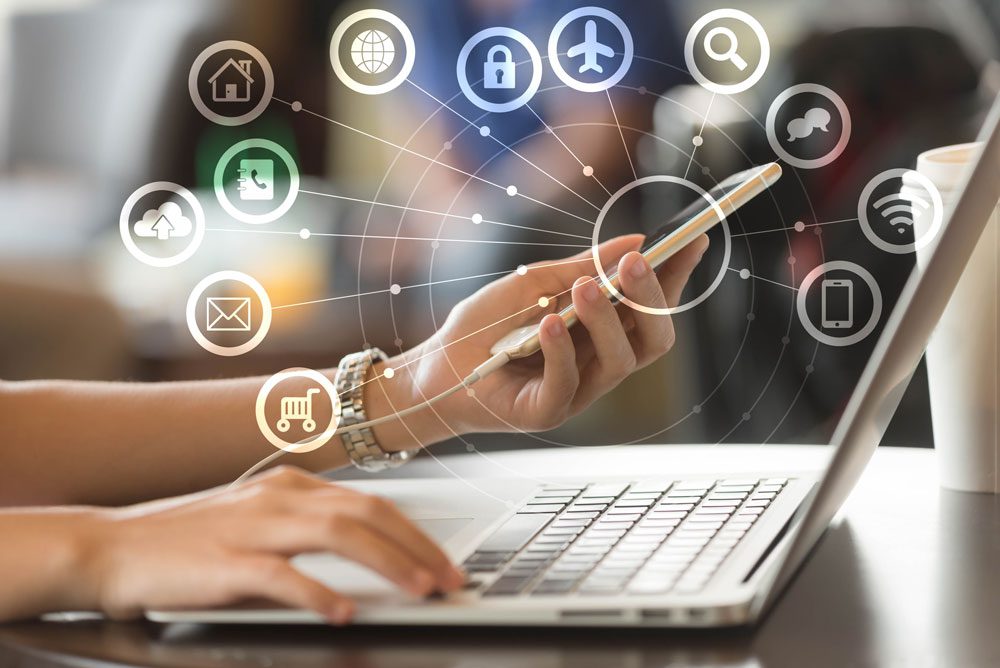 : A person browsing the web on a laptop while holding their mobile phone in their left hand