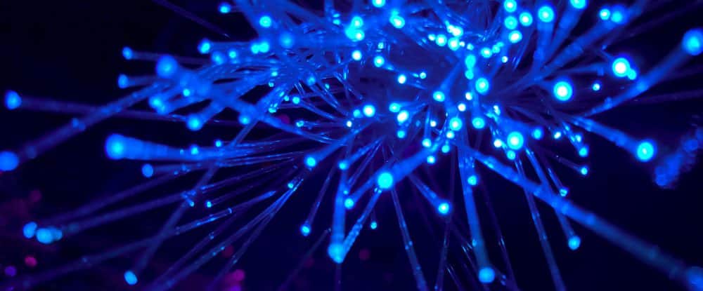 A close-up of optical fibers that are lit up with blue light