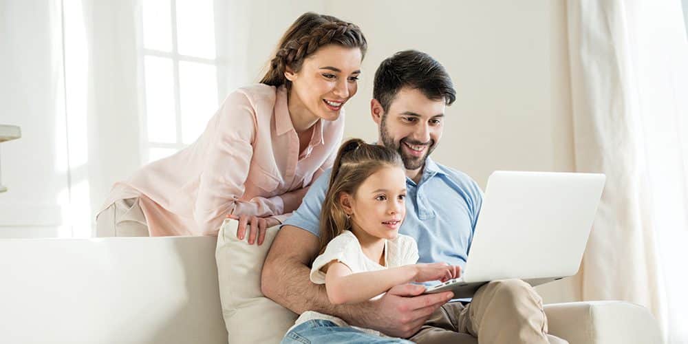 Young family of three gathered around laptop