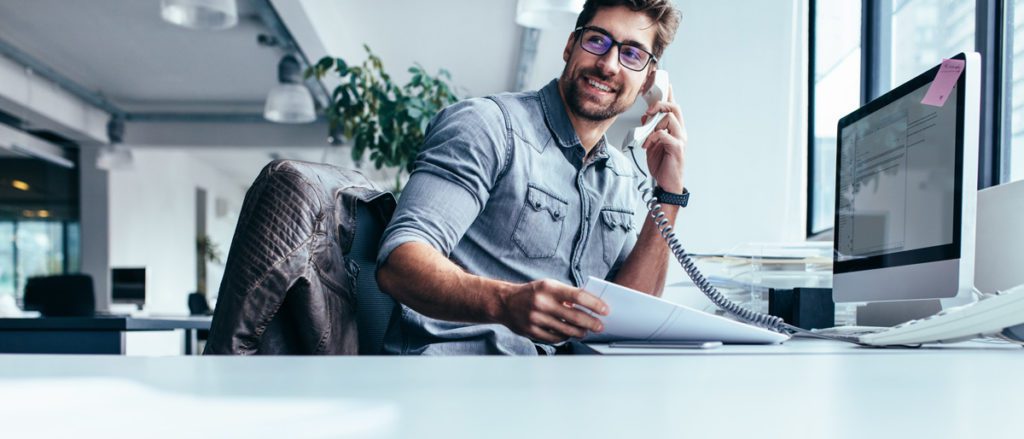 Business man at computer speaking on phone