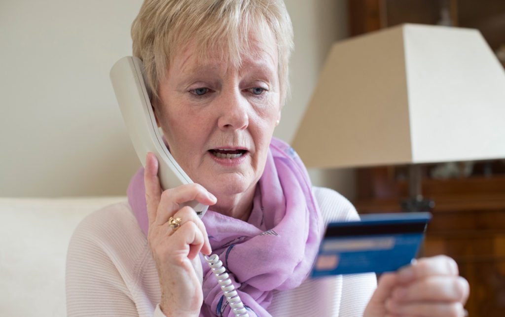 Senior woman on a corded phone giving her credit card information.