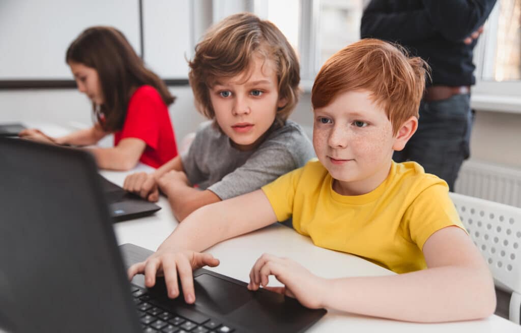Two Kids Club members using laptop together